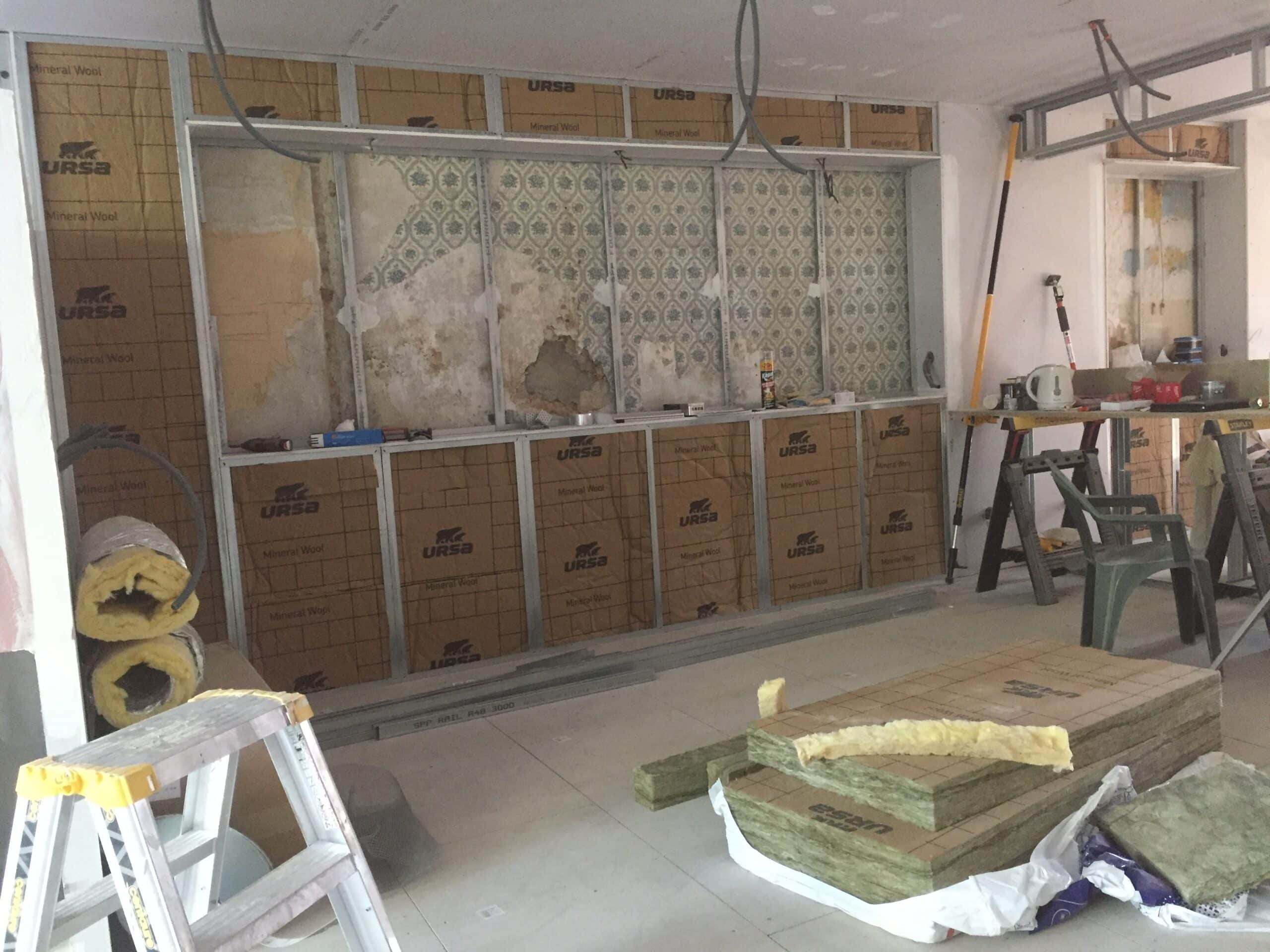 Pose isolation Ursa : Laine minérale et ossature métallique. Chantier de rénovation avec ossature métallique et panneaux d'isolation URSA (Mineral Wool) posés sur un vieux mur. Matériaux au sol.