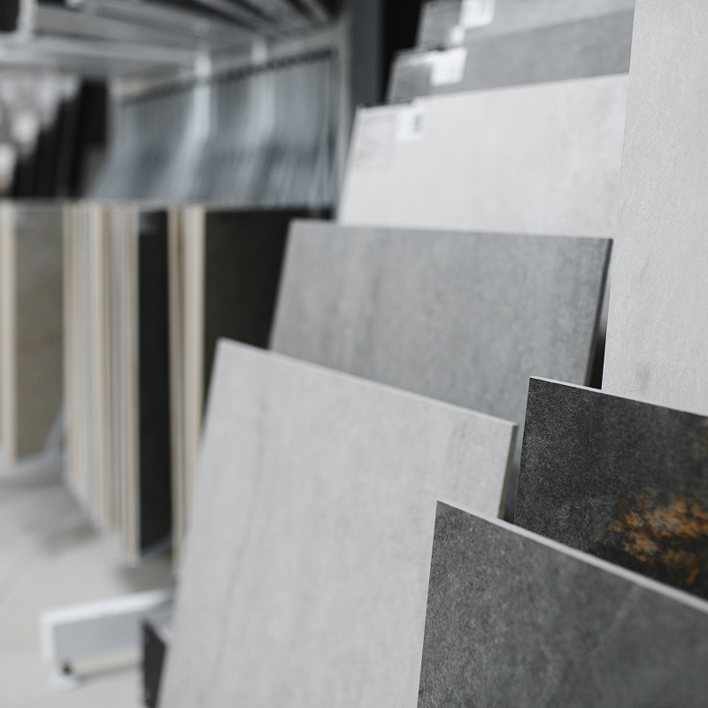 Nuancier de dalles de carrelage en grès cérame, du gris clair au anthracite, exposé sur un présentoir de magasin.