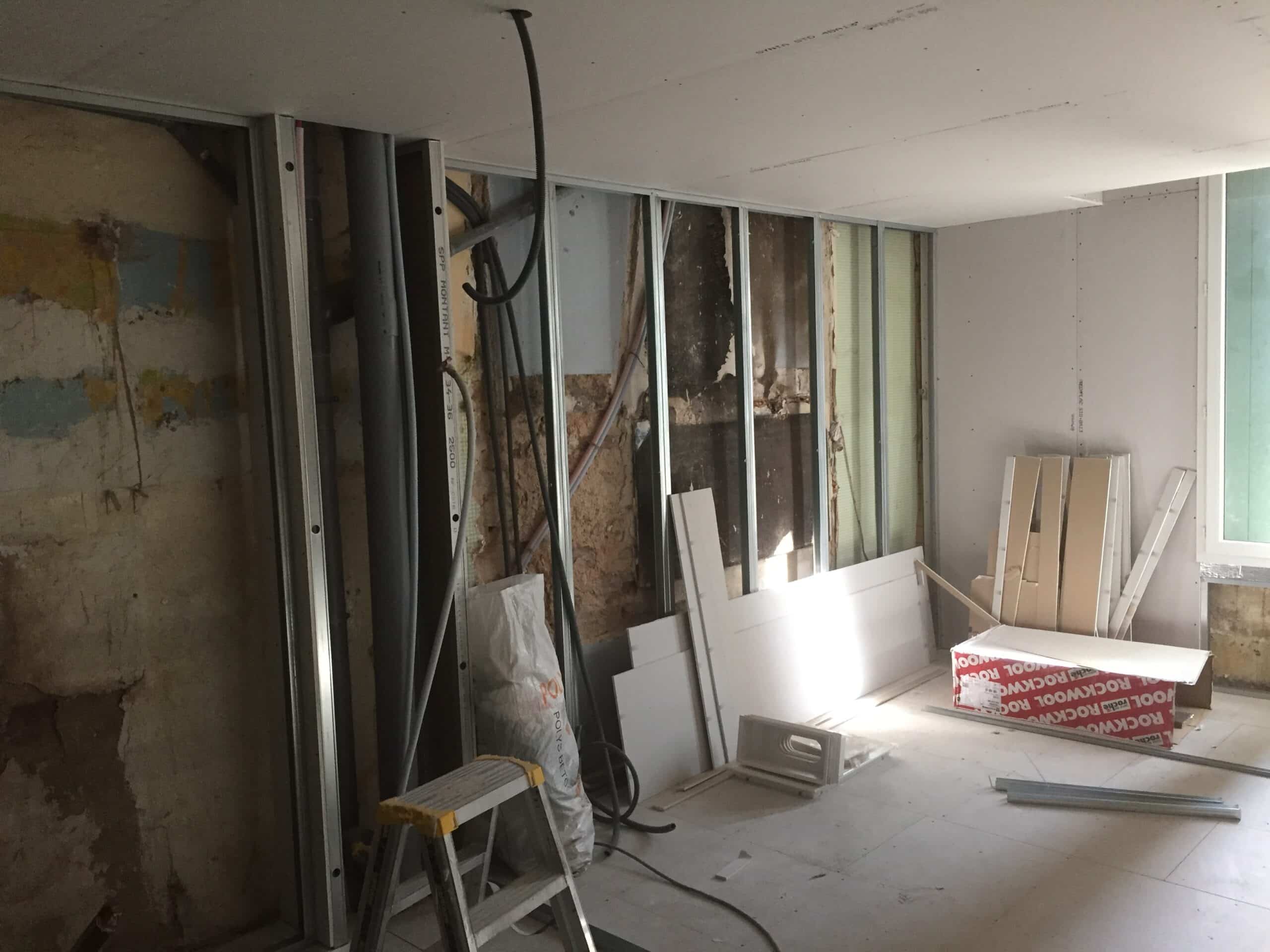 Chantier de rénovation intérieur. Ossature métallique pour placo, murs bruts exposés, tuyaux et boîte d'isolation Rockwool.