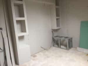 Étagères et niches en plaques de plâtre dans une pièce en cours de rénovation avec installation électrique apparente.