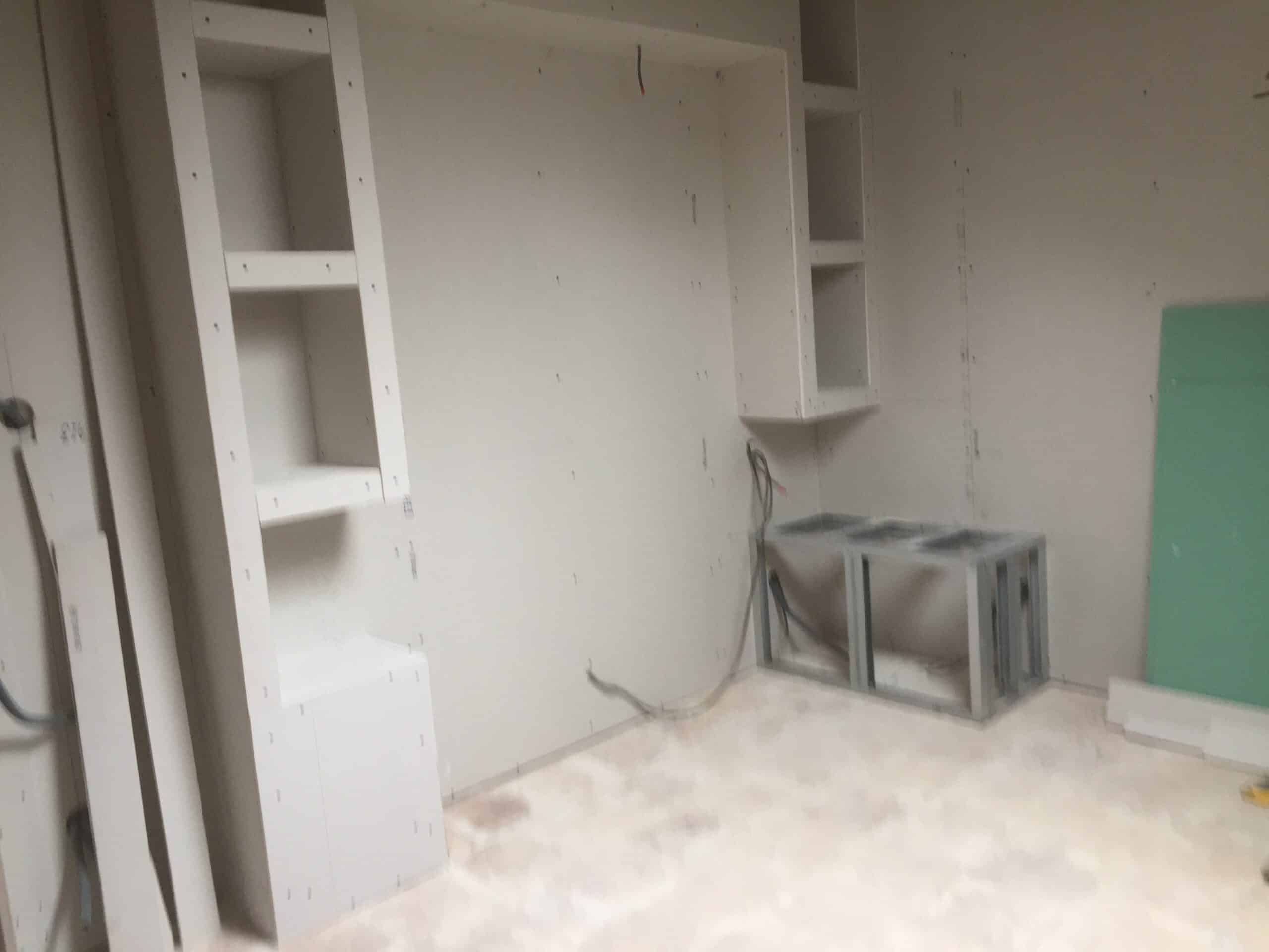 Étagères et niches en plaques de plâtre dans une pièce en cours de rénovation avec installation électrique apparente.