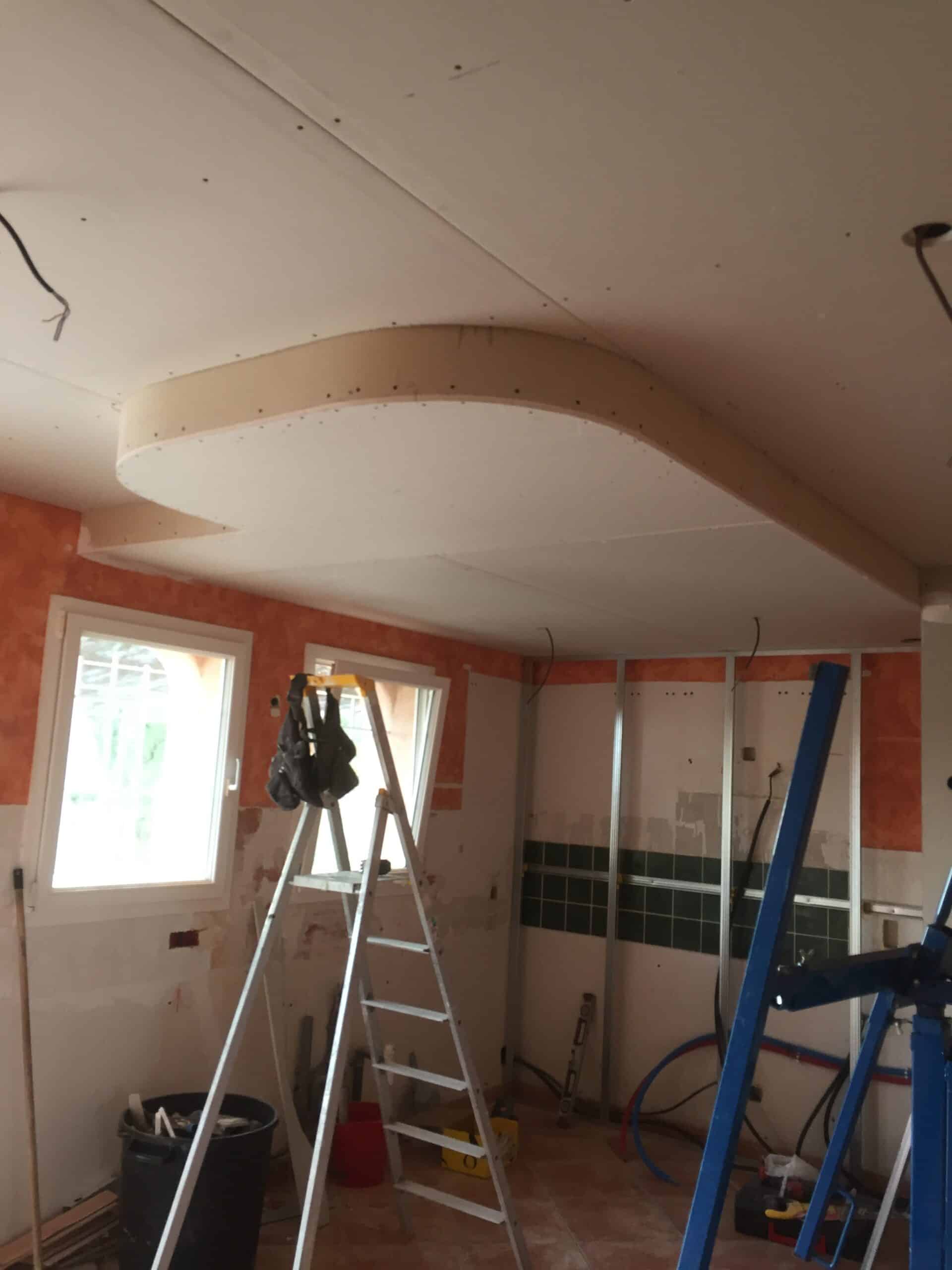 Installation d'un faux-plafond courbe en placoplatre lors de travaux de rénovation intérieure d'une pièce.