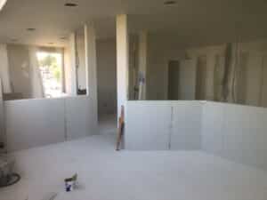 Chantier de rénovation avec cloisons en plaques de plâtre PREGYPLAC et outils de mesure dans une pièce lumineuse.