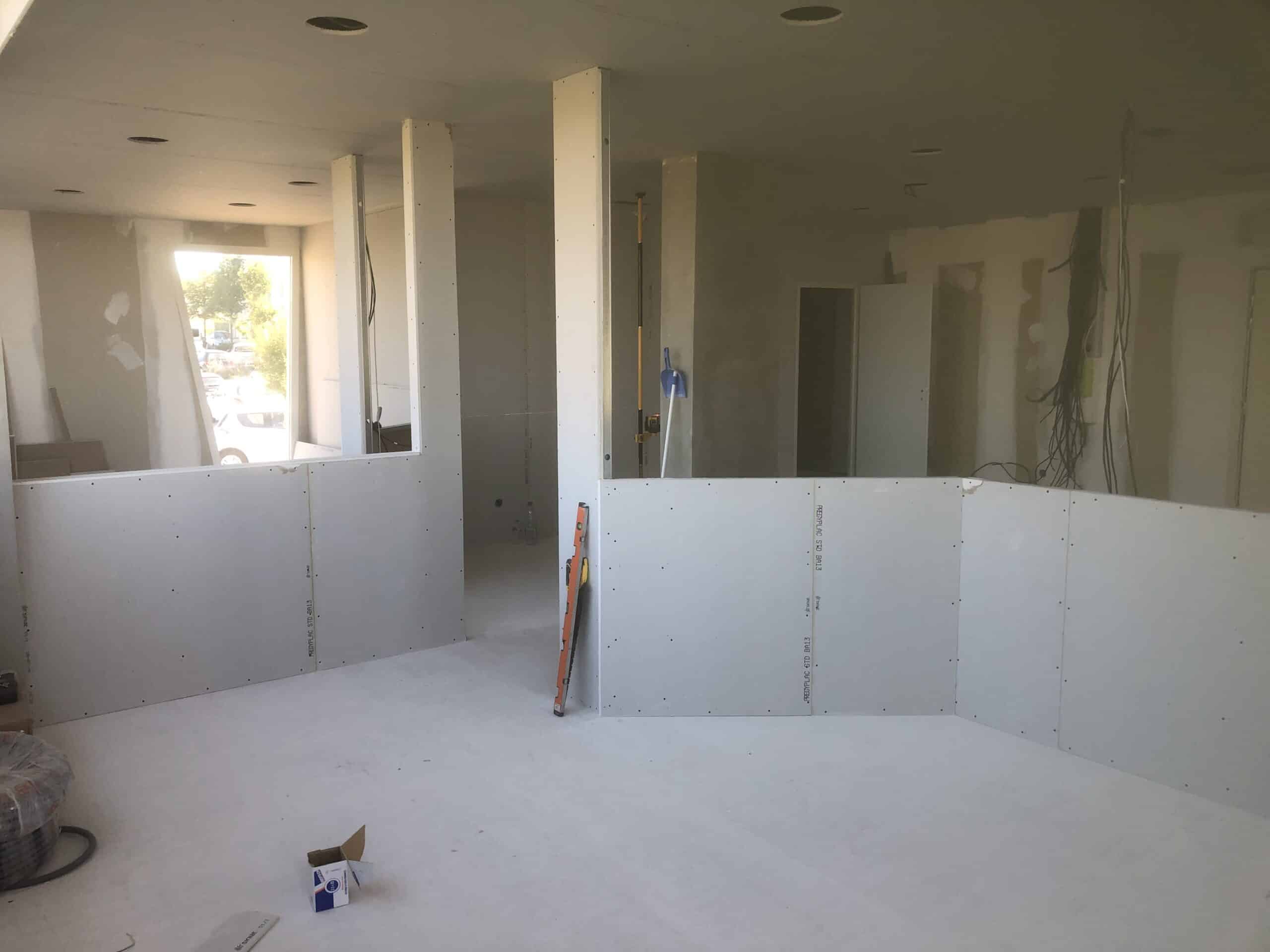 Chantier de rénovation avec cloisons en plaques de plâtre PREGYPLAC et outils de mesure dans une pièce lumineuse.
