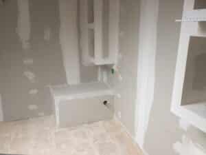 Mur en plaque de plâtre avec joints lissés et banquette intégrée lors d'une rénovation intérieure.