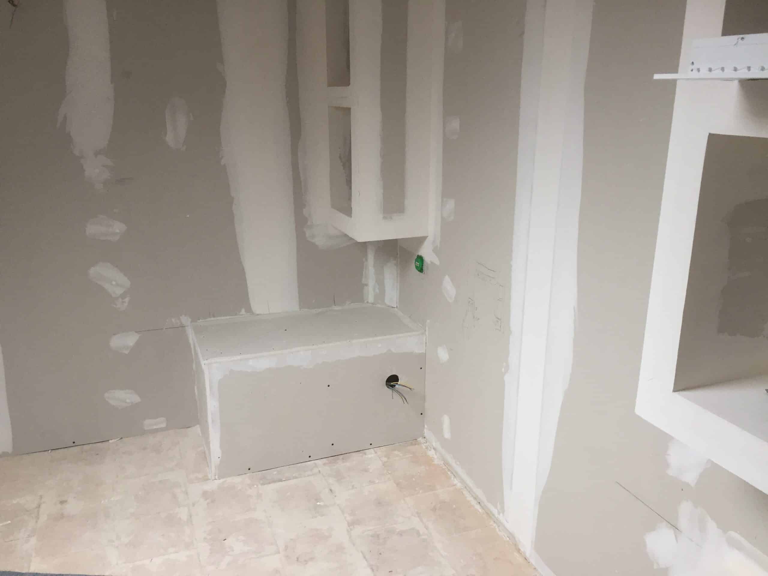 Mur en plaque de plâtre avec joints lissés et banquette intégrée lors d'une rénovation intérieure.